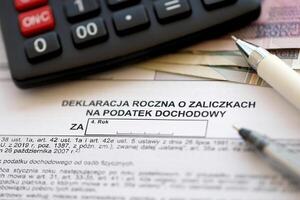 Annual declaration of income tax advances, PIT-4R form on accountant table with pen and polish zloty money bills photo