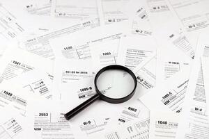 Magnifying glass lying over heap of paper documents. Investigation and financial audit photo