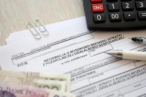 Information on amount of income or loss from non-agricultural economic activity, PIT-B form on accountant table with pen and polish zloty money bills photo