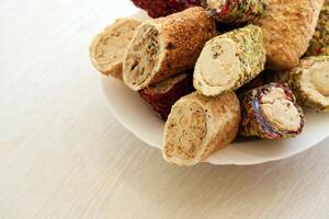 muchos rollos de turco deleite con diferente sabores y empastes en blanco plato en mesa. cortes de turco lokumu foto