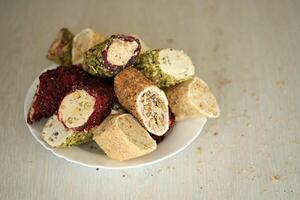 Many rolls of turkish delight with different flavors and fillings in white plate on table. Cuts of Turk Lokumu photo