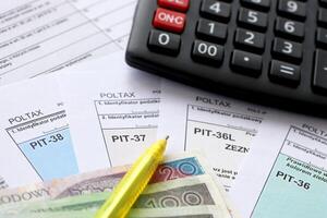 Declaration of the amount of earned income or incurred loss, PIT-36, PIT-36L, PIT-37 and PIT-38 tax forms on accountant table with pen and calculator photo