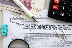 Declaration of amount of health insurance contributions paid and deducted from tax card in individual months of tax year, PIT-16A form on accountant table with pen and polish zloty money photo