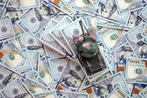Toy tank on US hundred dollar bills banknotes. The concept of war costs, military spending and economic crisis photo