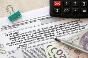 Information on revenue income derived by legal persons having no seats or place of management on territory of Poland IFT-2, IFT-2R form on accountant table with pen and polish zloty money photo