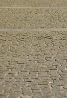 la textura de la losa de pavimentación adoquines de muchas piedras pequeñas de forma cuadrada bajo la luz del sol brillante foto