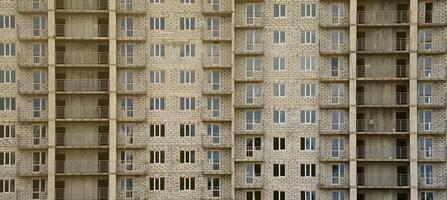 patrón texturizado de una pared de construcción de casas residenciales de piedra blanca rusa con muchas ventanas y balcón en construcción foto