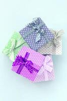 Pile of a small colored gift boxes with ribbons lies on a violet background. Minimalism flat lay top view photo