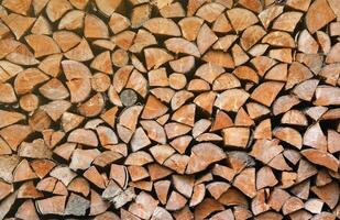 Firewood stacked near the wooden wall of old hut. Many chopped logs of firewood photo