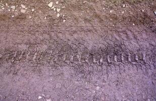 Wheel track on mud. Traces of a tractor or heavy off-road car on brown mud in wet meadow photo