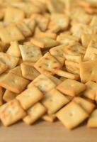 Background texture of small edible squares baked from dough and sprinkled with salt. A lot of salt cracker photo