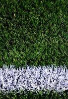 White stripe on a bright green artificial grass soccer field photo