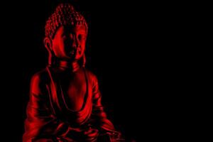 Buda purnima y vesak día concepto, rojo Buda estatua con bajo llave ligero en contra profundo negro antecedentes foto