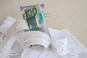 Euro bills bunch in shopping trolley surrounded by many paper receipts photo