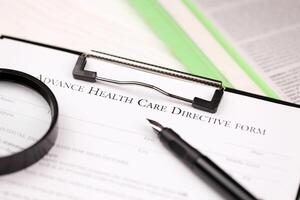 Advance health care directive blank form on A4 tablet lies on office table with pen and magnifying glass photo