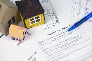 Residential construction agreement ready to sign with small toy houses and pen. Construction contract photo