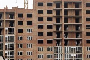 ver de un grande construcción sitio con edificios debajo construcción y de muchos pisos residencial casas torre grúas en acción en azul cielo antecedentes. alojamiento renovación concepto foto