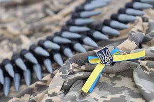 ucranio símbolo y un máquina pistola cinturón en el camuflaje uniforme de un ucranio soldado. el concepto de guerra en Ucrania, patriotismo y proteger tu país desde ocupantes foto