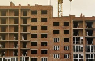 View of a large construction site with buildings under construction and multi-storey residential homes. Tower cranes in action on blue sky background. Housing renovation concept photo