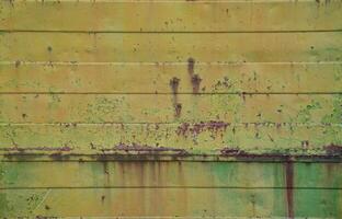 Texture of an old yellow metal wall with significant damage from exposure to unfavorable weather conditions and dampness photo