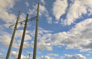 poste de hormigón con cables de línea eléctrica contra el fondo del cielo azul nublado foto