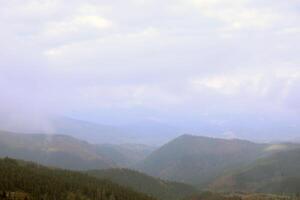 Morning view from the Dragobrat mountain peaks in Carpathian mountains, Ukraine. Cloudy and foggy landscape around Drahobrat Peaks photo