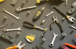 Handyman tool kit on black wooden table. Many wrenches and screwdrivers, pilers and other tools for any types of repair or construction works. Repairman tools photo