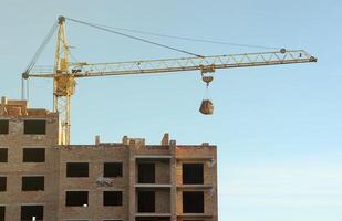 View of a large construction site with buildings under construction and multi-storey residential homes. Tower cranes in action on blue sky background. Housing renovation concept photo