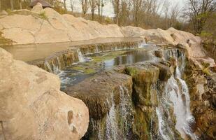 Beautiful waterfall between large rocks in autumn forest. Sofievskiy park in Uman, Ukraine photo