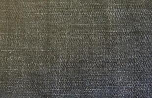 Detailed abstract texture of dark blue denim cloth. Background image of old used denim trousers fabric photo