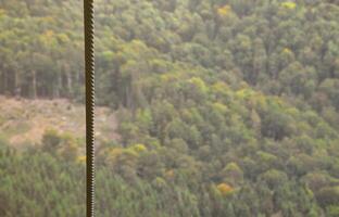 Iron cable from the transportation system of the funicular on the background of a green mountain forest photo