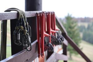 large metal locking carabiners with rope, climbing gear hanging on the store room. Height safety harness and arborist equipment photo