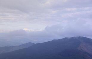 Morning view from the Dragobrat mountain peaks in Carpathian mountains, Ukraine. Cloudy and foggy landscape around Drahobrat Peaks photo