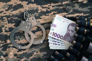 Ukrainian army machine gun belt shells and handcuffs on military uniform. Concept of bribery and war crimes photo