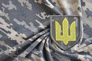 Symbol of Ukrainian army on the camouflage uniform of a Ukrainian soldier. The concept of war in Ukraine, patriotism and protecting your country from occupiers photo