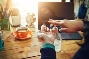 Women using laptop working and clean hands with alcohol drink coffee cup hot at home photo