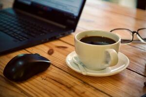 mujer utilizando ordenador portátil trabajando y bebida café taza caliente a hogar foto