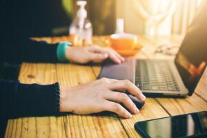 Women using laptop working clean hands with alcohol and drink coffee cup hot in the morning photo