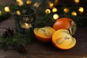 Bright orange persimmons sliced on the wooden background photo