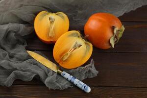 Bright orange persimmons sliced on the wooden background photo