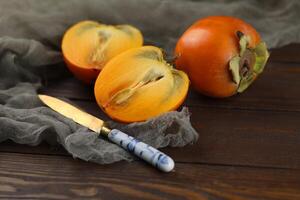 Bright orange persimmons sliced on the wooden background photo