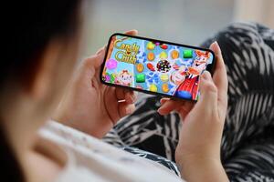 Candy Crush Saga mobile iOS game on iPhone 15 smartphone screen in female hands during mobile gameplay photo