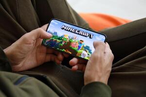 Minecraft mobile iOS game on iPhone 15 smartphone screen in male hands during mobile gameplay photo