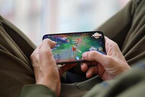 Honor of Kings mobile iOS game on iPhone 15 smartphone screen in male hands during mobile gameplay photo
