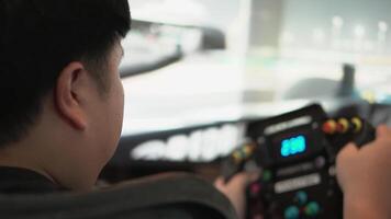 A young man with race car video player game with big screen monitors and cockpit controls like a racing car.