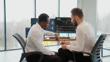 Two diverse men in formalwear working using computers while sitting in the office video