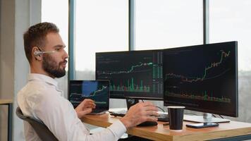 Concentrated trader sitting in front of computers, making professional analysis of candlestick chart, creating strategy video