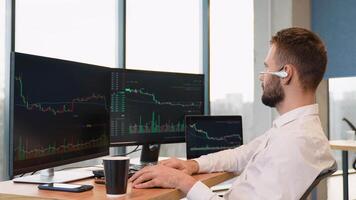 Trader or broker in formal wear working with charts and market reports on computer screens in his modern office video