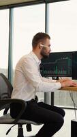 Trader or broker in formal wear working with charts and market reports on computer screens in his modern office. Vertical video