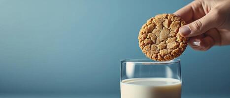 AI generated Close-Up of a Hand Holding a Cookie, Glass of Milk. Set Against a Vibrant Blue Background, Bright Lighting Enhances the Anticipation of the Dunking Moment. photo